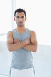 Fit young man standing with arms crossed in fitness studio