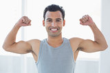 Fit young man flexing muscles in fitness studio