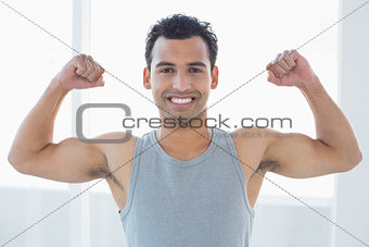 Fit young man flexing muscles in fitness studio