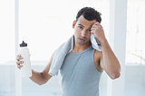 Young man wiping sweat with towel in fitness studio