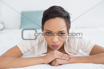 Serious pretty young woman relaxing in bed