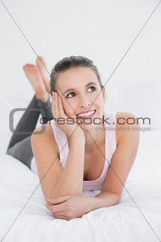 Thoughtful smiling woman relaxing in bed