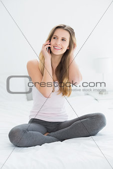 Beautiful smiling woman using cellphone in bed