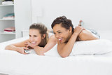 Cheerful female friends with remote control lying in bed