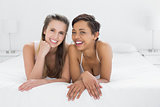 Portrait of smiling young female friends in bed