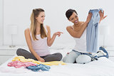 Pretty female friends selecting clothes in bed