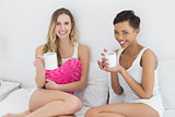 Female friends with coffee cups in bed