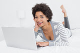 Pretty young woman using laptop in bed
