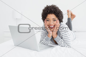 Smiling pretty woman with laptop in bed