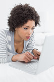 Close-up of a serious woman using laptop in bed