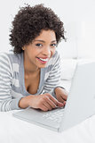 Close-up of a smiling woman using laptop in bed