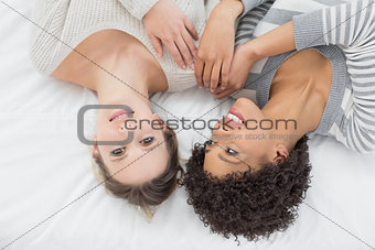 Casual young female friends lying in bed