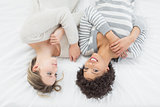 Two casual young female friends lying in bed