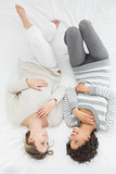 Cheerful young female friends lying in bed