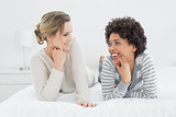 Relaxed smiling female friends lying in bed