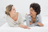Two relaxed smiling female friends lying in bed