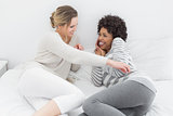 Relaxed female friends enjoying a conversation in bed