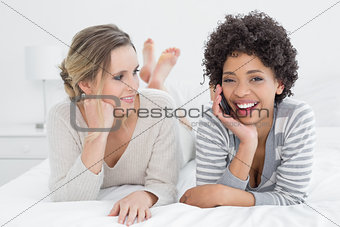 Woman looking at cheerful friend on call in bed