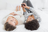 Two relaxed female friends reading text message in bed