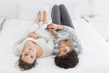 Relaxed female friends with mobile phone in bed