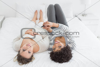 Relaxed female friends with mobile phone in bed
