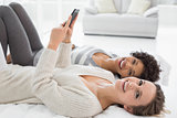 Relaxed female friends reading text message in bed