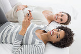 Relaxed female friends reading text message in bed