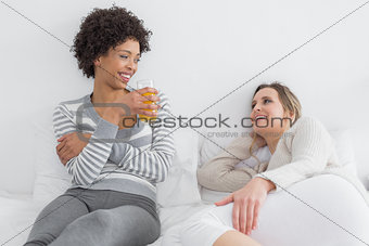 Smiling young female friends chatting in bed