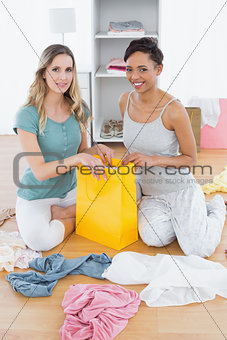 Smiling women sitting on floor with shopping bag
