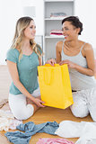 Smiling women sitting on floor with shopping bag