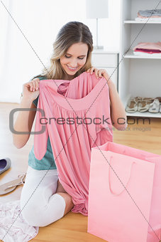 Woman sitting on floor with new dress and shopping bag
