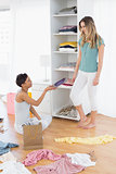 Happy young women arranging clothes in shelf