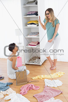 Two happy women with clothes on floor