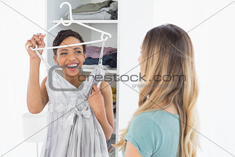 Cheerful woman showing a dress to her friend