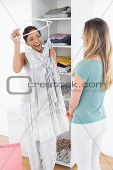 Cheerful woman showing a dress to her friend