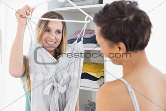 Happy woman showing a dress to her friend