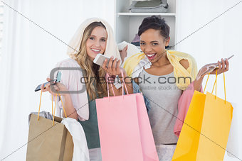 Cheerful women standing with shopping bags at home