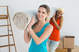 Female friends carrying rolled rug after moving in a house
