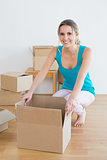 Happy young woman unwrapping boxes in new house