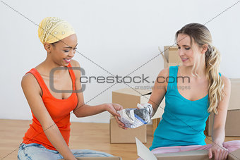 Happy friends unwrapping boxes in a new house