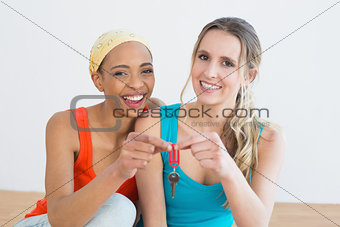 Portrait of two cheerful female friends with house keys