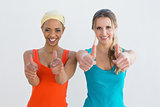 Portrait of two young female friends gesturing thumbs up