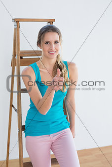 Woman gesturing thumbs up against ladder in a new house