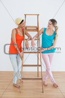 Female friends with a ladder in a new house