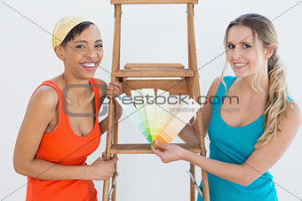 Friends with ladder choosing color for painting a room