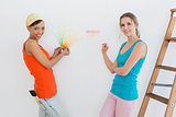 Happy friends with ladder choosing color for painting a room