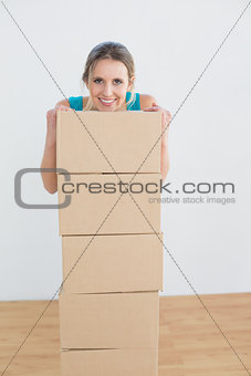 Smiling woman with a stack of boxes in new house