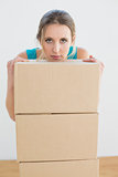 Serious woman with a stack of boxes in new house