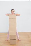 Smiling woman moving in a new house with a stack of boxes