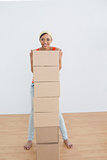 Smiling woman moving in a new house with a stack of boxes